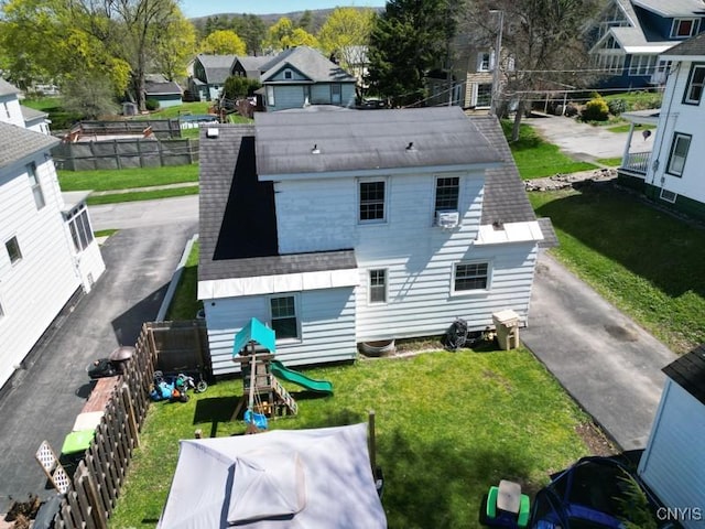 back of house with fence, a lawn, and a residential view