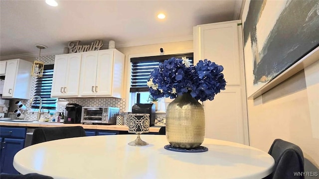 kitchen featuring white cabinetry, tasteful backsplash, a sink, light countertops, and a toaster