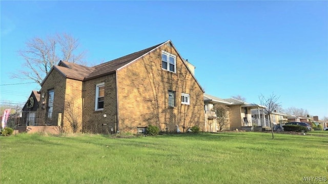 view of home's exterior with brick siding and a lawn
