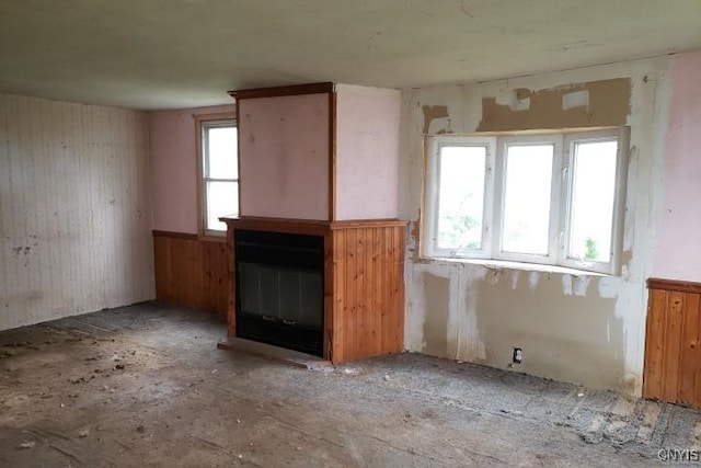 24 Railroad St, Elbridge, NY 13080 - unfurnished living room featuring a wainscoted wall, a wealth of natural light, wooden walls, and a glass covered fireplace
