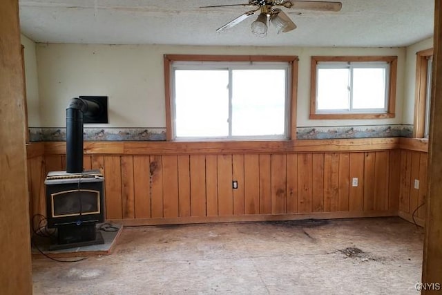 24 Railroad St, Elbridge, NY 13080 - interior space featuring wooden walls, a wood stove, a wainscoted wall, and ceiling fan