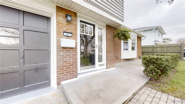 entrance to property featuring brick siding and fence