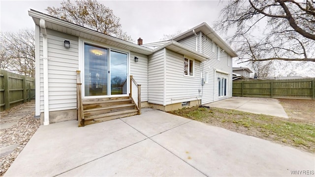 rear view of house featuring a chimney, a patio, entry steps, and a fenced backyard