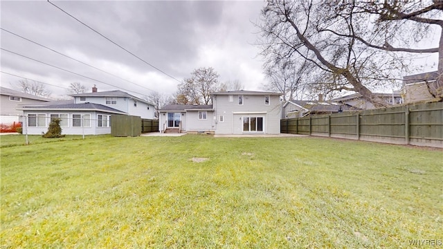 rear view of property featuring fence, a patio area, and a lawn