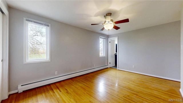 empty room featuring a baseboard radiator, wood finished floors, ceiling fan, and baseboards