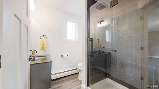 bathroom with a shower stall, a baseboard heating unit, toilet, and vanity