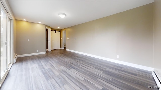 spare room with a baseboard heating unit, baseboard heating, baseboards, recessed lighting, and wood finished floors