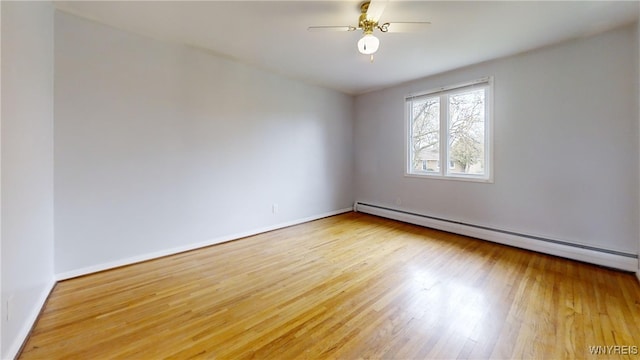 unfurnished room featuring baseboards, a ceiling fan, wood finished floors, and a baseboard heating unit