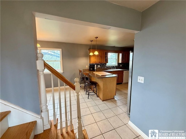 kitchen featuring a kitchen bar, a sink, a peninsula, and a wealth of natural light