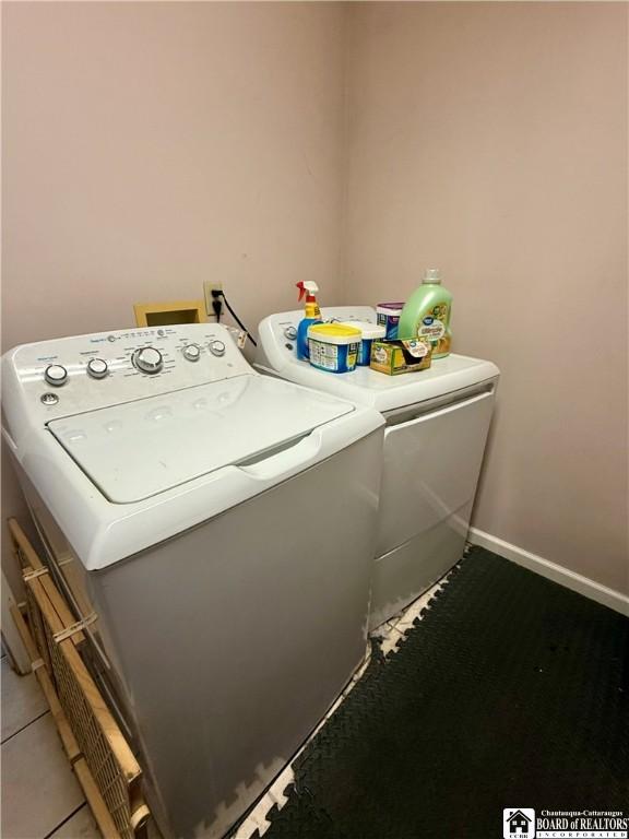 washroom featuring washing machine and dryer, laundry area, and baseboards