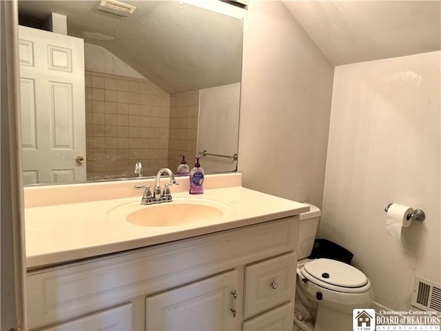 bathroom featuring toilet, vanity, visible vents, and lofted ceiling