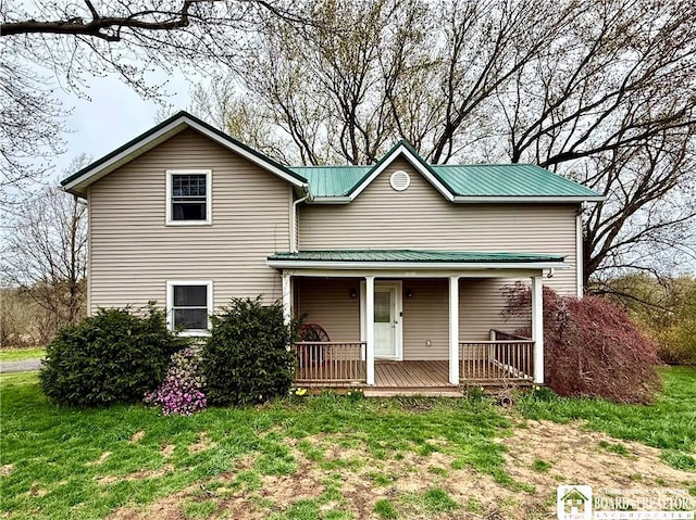 traditional home featuring metal roof, a front yard, and covered porch