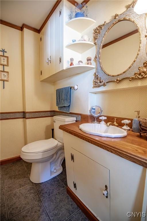 bathroom with toilet, tile patterned flooring, crown molding, and vanity
