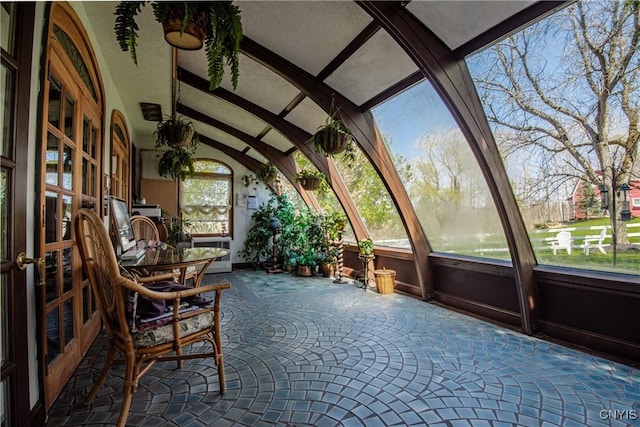 unfurnished sunroom featuring vaulted ceiling with beams