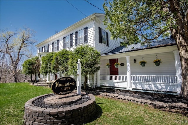 view of front of house with a porch, a front lawn, and metal roof