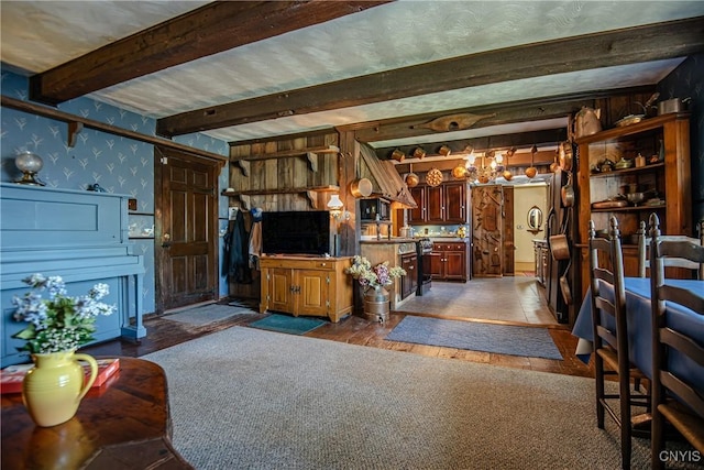 interior space featuring wood finished floors, beamed ceiling, and wallpapered walls