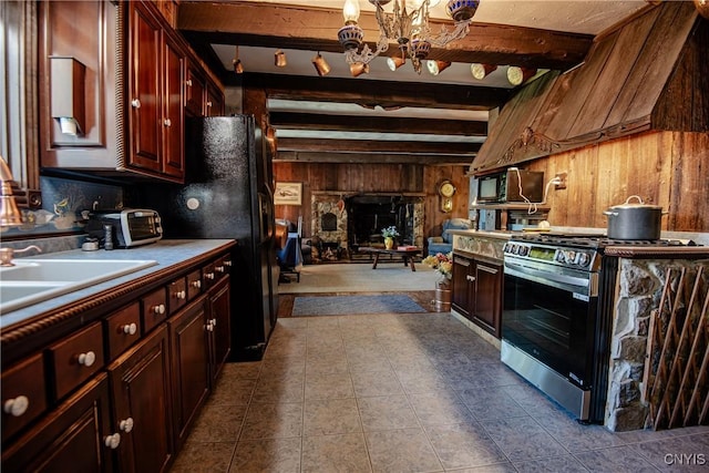 kitchen featuring beam ceiling, a chandelier, wooden walls, black appliances, and open floor plan