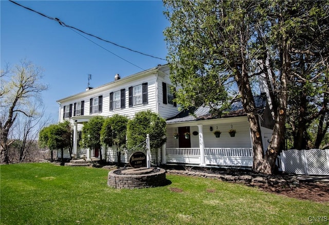 colonial inspired home featuring covered porch and a front yard