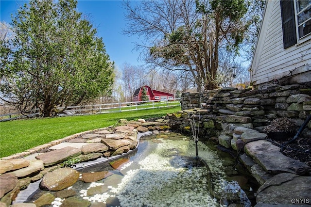 view of yard with fence and a garden pond