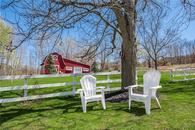 view of yard featuring driveway, an outdoor structure, a barn, a detached garage, and fence