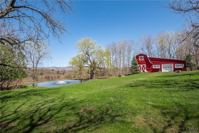view of yard with an outbuilding, a detached garage, a water view, and a barn