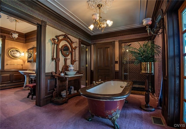 full bath featuring visible vents, ornamental molding, a freestanding tub, a decorative wall, and a notable chandelier