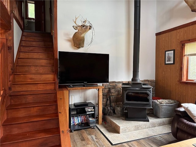 living area with stairs, wood walls, wood finished floors, and a wood stove
