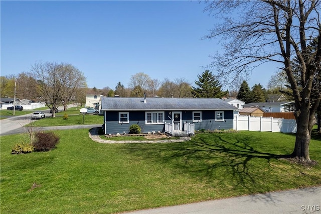ranch-style home with fence, a front yard, and a shingled roof