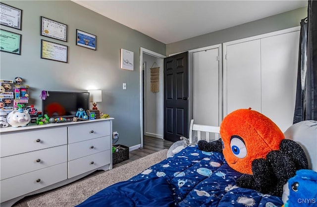 bedroom featuring multiple closets, wood finished floors, and baseboards