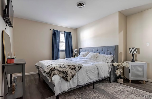 bedroom with wood finished floors, visible vents, and baseboards