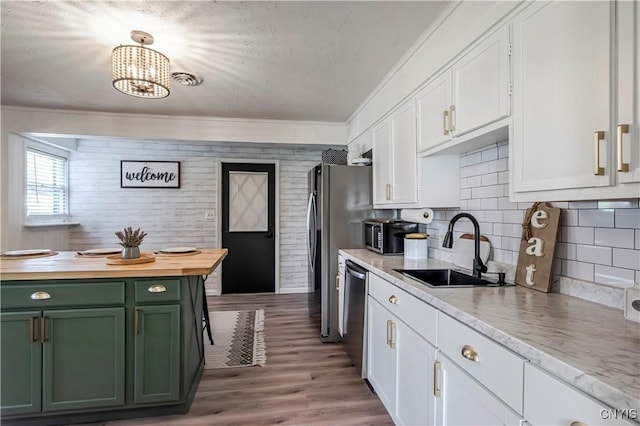 kitchen with a sink, butcher block countertops, stainless steel dishwasher, green cabinetry, and white cabinets