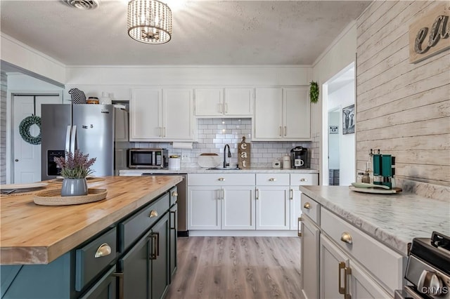 kitchen with wood counters, white cabinetry, a chandelier, and appliances with stainless steel finishes