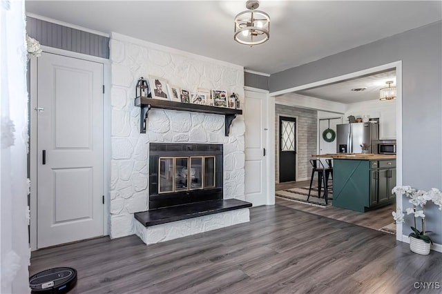 living room with crown molding, dark wood-style floors, and a fireplace
