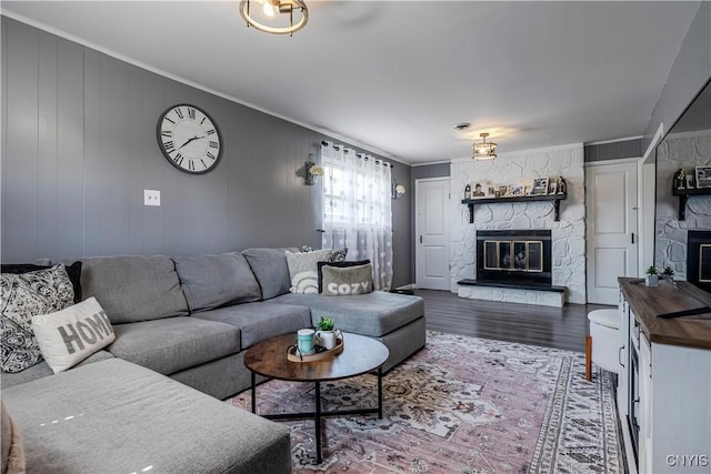 living room featuring ornamental molding, a stone fireplace, and wood finished floors