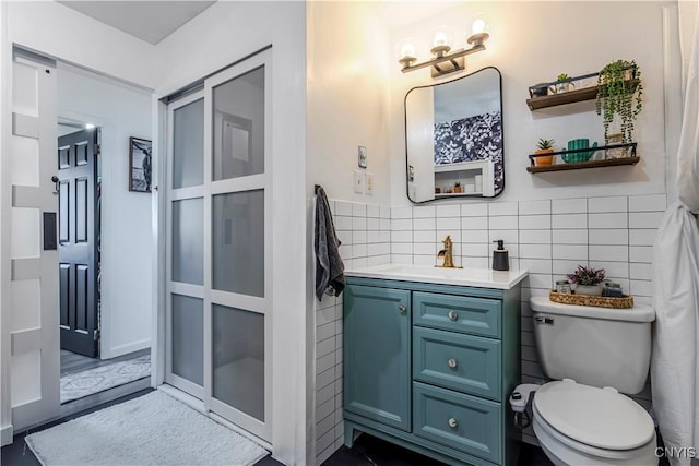 bathroom featuring vanity, toilet, and tile walls