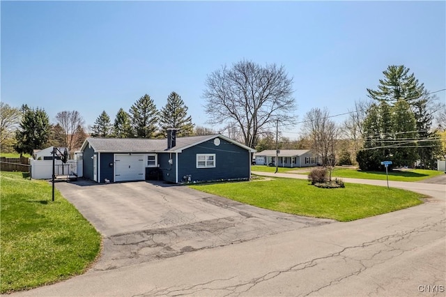 view of front of property featuring a front yard, driveway, a garage, and fence