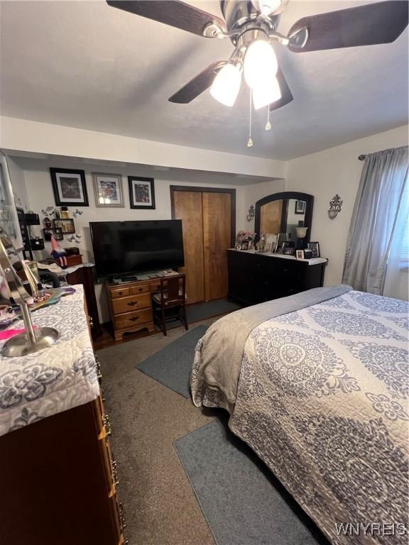 bedroom with a ceiling fan and dark carpet