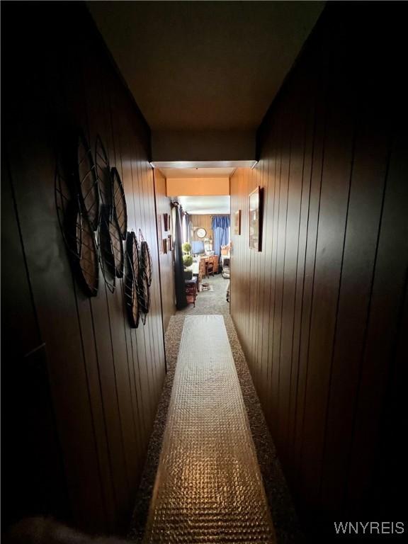 hallway featuring wooden walls