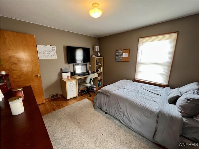 bedroom featuring wood finished floors and visible vents