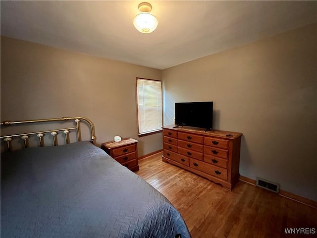 bedroom with visible vents, light wood-type flooring, and baseboards