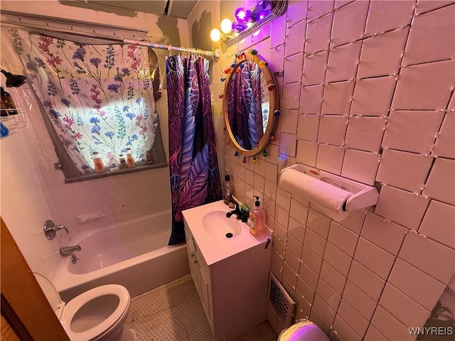 bathroom featuring shower / bath combo, toilet, tile walls, vanity, and tile patterned flooring