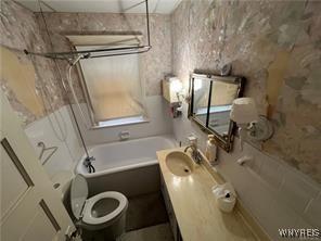 bathroom featuring walk in shower, a tub, toilet, and vanity