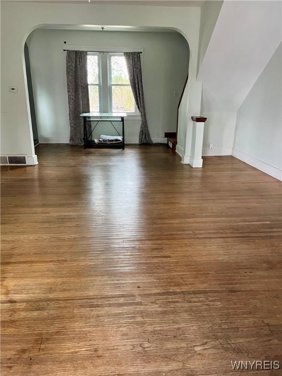 interior space featuring arched walkways, hardwood / wood-style floors, baseboards, and visible vents