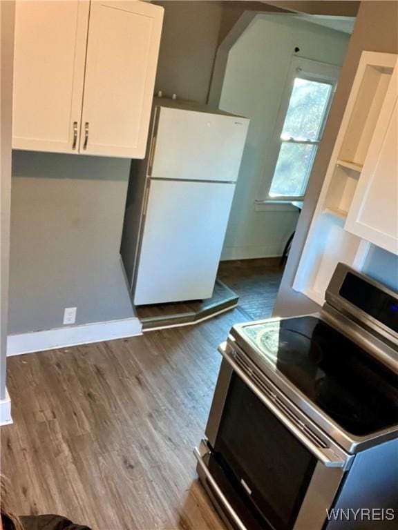kitchen featuring white cabinets, dark wood-style floors, freestanding refrigerator, baseboards, and electric stove
