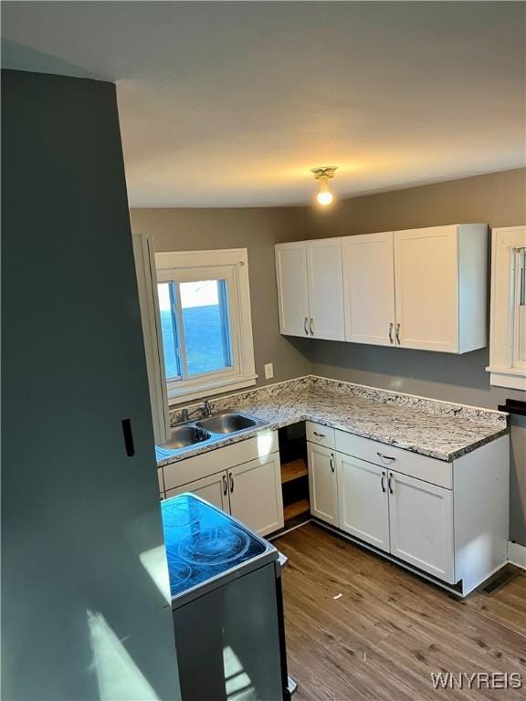 kitchen with dark wood finished floors, white cabinets, electric range oven, and a sink