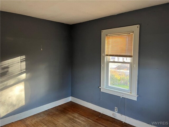 empty room with dark wood-style flooring and baseboards