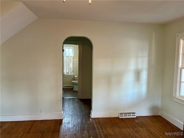 spare room with visible vents, plenty of natural light, hardwood / wood-style floors, and arched walkways