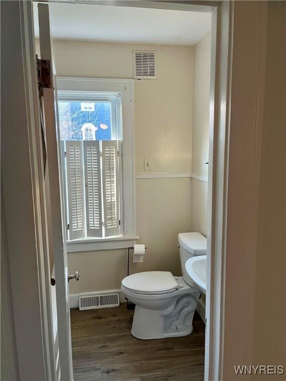bathroom featuring baseboards, visible vents, wood finished floors, and toilet