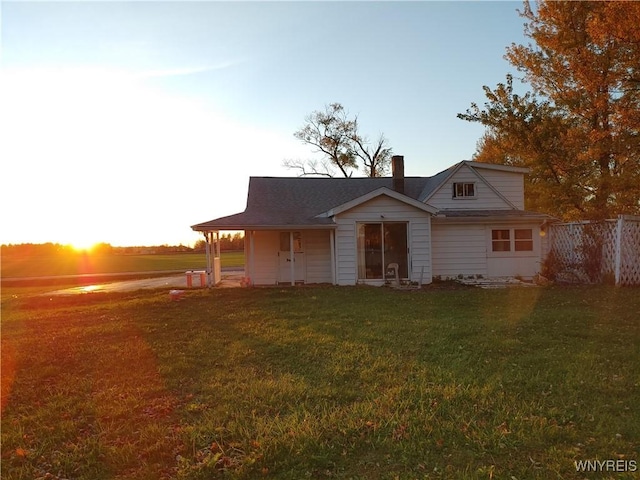 view of front of home featuring fence, a chimney, and a front yard