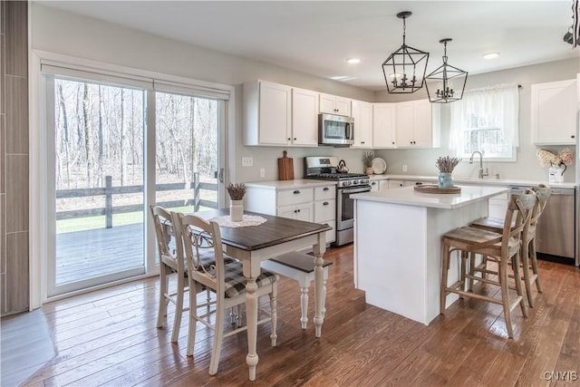 kitchen featuring a center island, white cabinetry, stainless steel appliances, and a sink